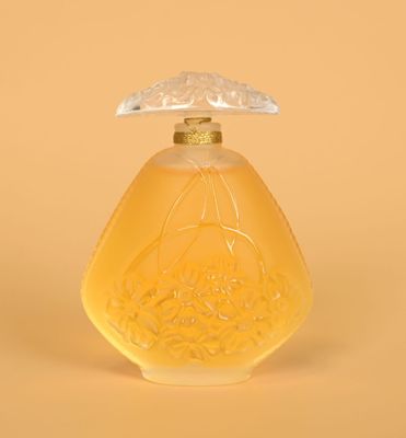 yellow glass perfume bottle with a clear lid on a yellow background