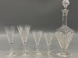 five wine glasses and a decanter on a table