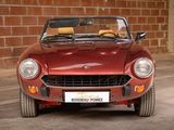 a red sports car parked in front of a brick wall