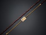 un collier composé de perles dorées et rouges, muni d'un fermoir plaqué or