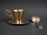 a silver cup and a spoon on a black table