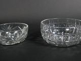 pair of cut glass bowls on a black background