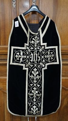 un gilet noir et blanc orné d'une croix, suspendu à une porte en bois