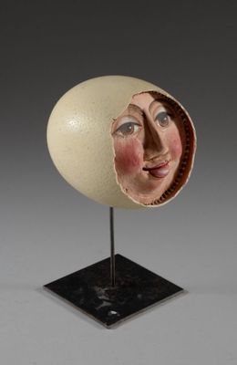 sculpture représentant le visage d'une femme dans une coquille d'œuf, posée sur un socle noir