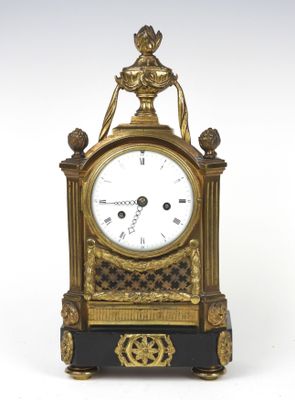 une horloge dorée et noire posée sur une surface blanche