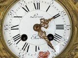 a gold clock with roman numerals on the face