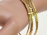 gold plated bang bracelets on a female ' s hand on a mannequin mannequin mannequin mannequin mannequin mannequin