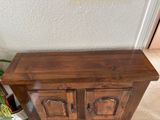 a small wooden cabinet with two doors and a potted plant in the corner