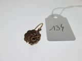 une étiquette ornée d'une fleur, à côté d'une paire de boucles d'oreilles