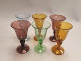 four different colored glass goblets sitting on top of a white surface