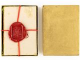 an open box with a wax seal in it on a white surface