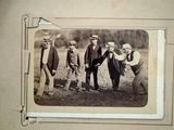 four men standing together in a field with a dog