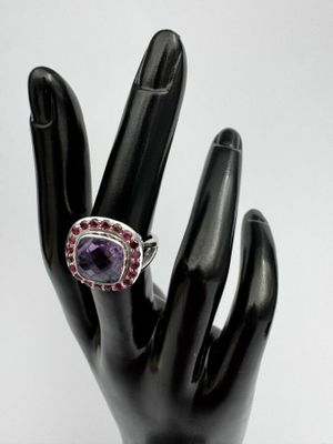 une image représentant une bague ornée d'une pierre violette posée sur une main