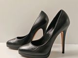 une paire de chaussures noires à talons hauts posée sur une surface blanche