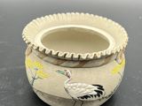 a small vase with a bird on it on a table
