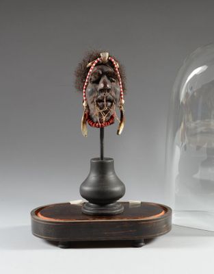une image représentant une statue d'un homme coiffé d'une coiffe, posée sur un socle en bois