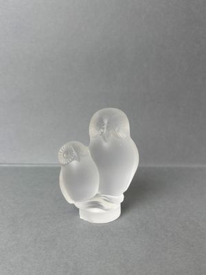 two glass birds sitting on top of each other on a table