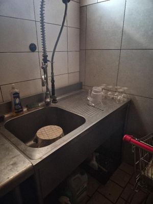 a sink with a faucet and a shopping cart in the corner