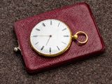 une montre de poche posée sur un étui rouge