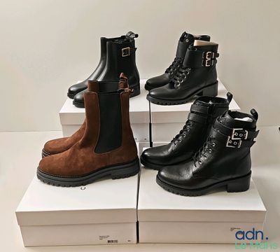 trois paires de bottes noires et marron posées sur des cartons