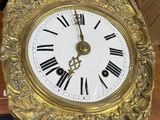a gold clock with roman numerals on the face