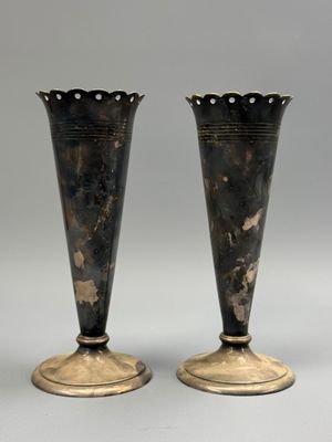 pair of antique silver vases on pedestals against a gray background