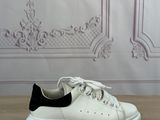 des baskets blanches et noires posées sur une table en bois devant un mur