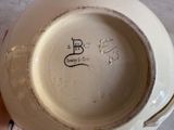someone is holding a white bowl with a black design on it