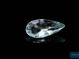 un gros plan d'un diamant transparent posé sur une surface noire