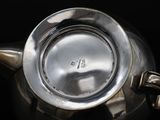 a silver tea pot with a handle on a black surface
