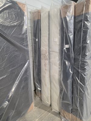 de nombreux matelas emballés dans du plastique, posés par terre