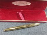 a gold pen in a red case on a blue surface
