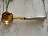 a gold spoon on a marble table with a silver handle