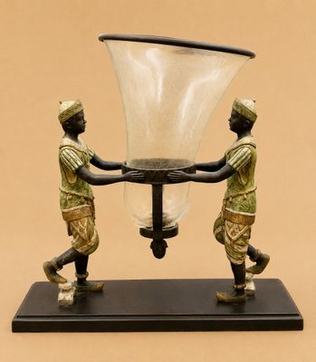 statue représentant deux hommes tenant un grand vase en verre posé sur un socle noir