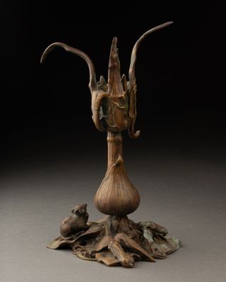 une sculpture en bronze représentant une tête de chèvre posée sur une souche d'arbre