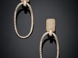 a pair of silver and gold earrings on a black background