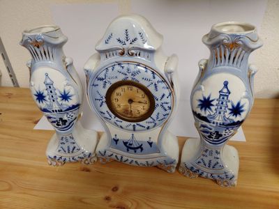 three blue and white vases with a clock on them