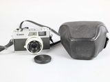a camera and a coin on a white surface