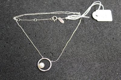 silver necklace with a heart and a pearl on a black surface