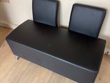 un banc en cuir noir sur lequel sont posées deux chaises noires
