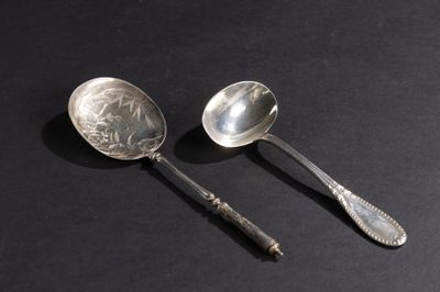 une paire de cuillères en argent posées sur une surface noire, sur fond noir