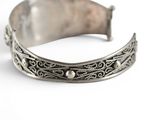 an image of a close up of a silver bracelet on a white surface