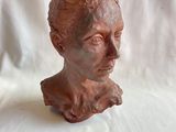 une sculpture en argile représentant la tête d'une femme sur fond blanc
