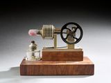 une petite maquette de machine à vapeur posée sur un socle en bois
