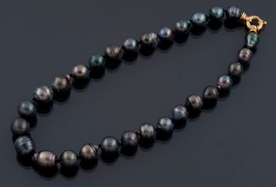 un gros plan d'un collier de perles noires posé sur une surface noire
