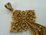 a close up of a gold pendant on a white surface