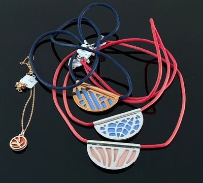 Plusieurs colliers et bracelets sont disposés sur une surface noire