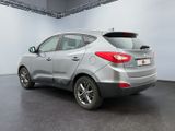 the back of a silver car in a room with a white wall