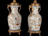 pair of antique vases with gilded handles on stands against a black background
