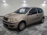 the small beige car is parked in the room on the checkered floor